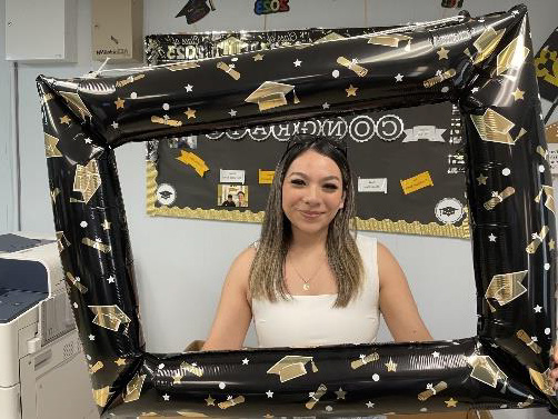 Female student smiling holding a graduation frame