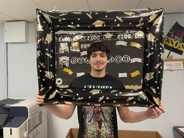 Male student smiling holding a graduation frame