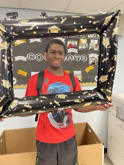 Male student smiling holding a graduation frame